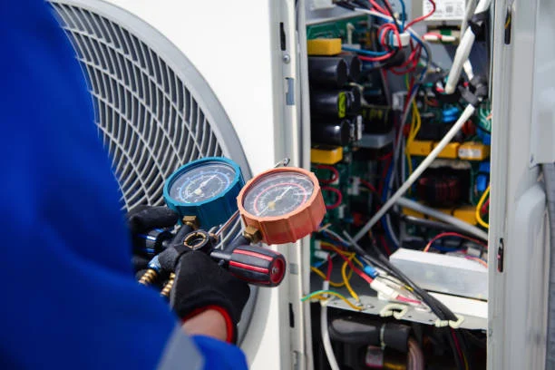 Technician reading pressure gauges beside a control board